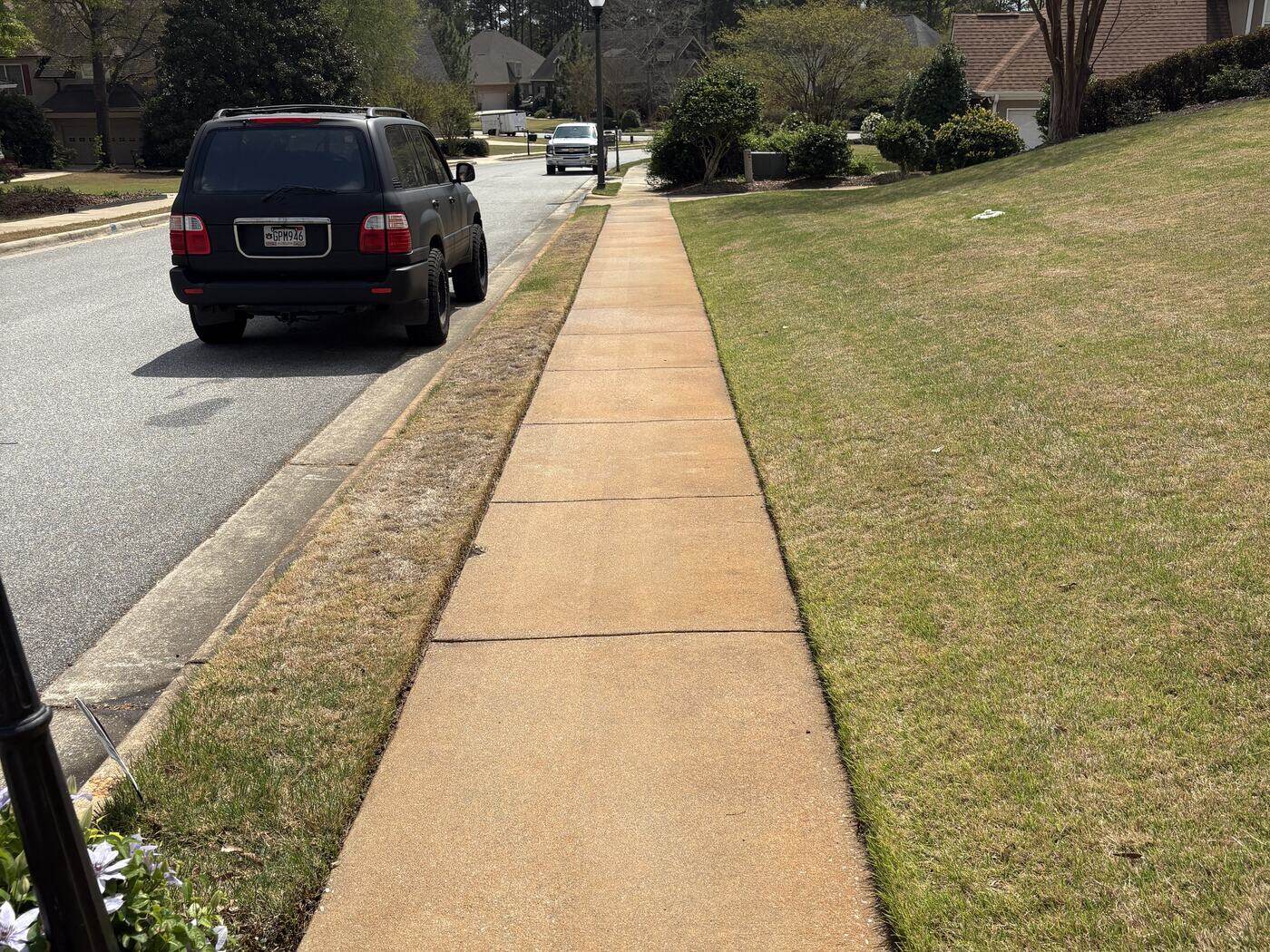 A residential sidewalk in Auburn after pressure washing, with the concrete restored to an even light tan